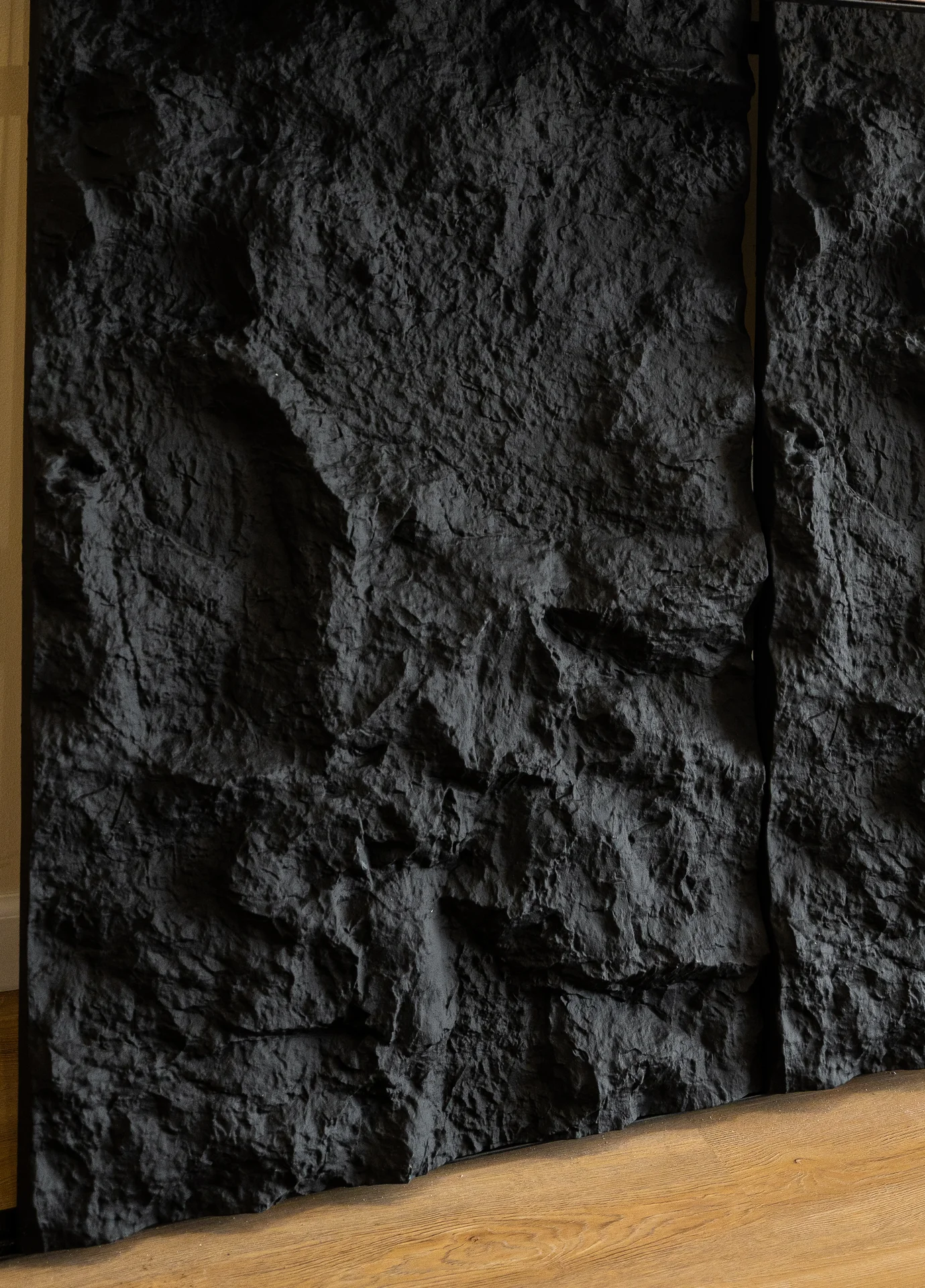 Textured black wall panels with a rough, rock-like finish next to light wood flooring. by PVC Global Imports USA LLC in Carte