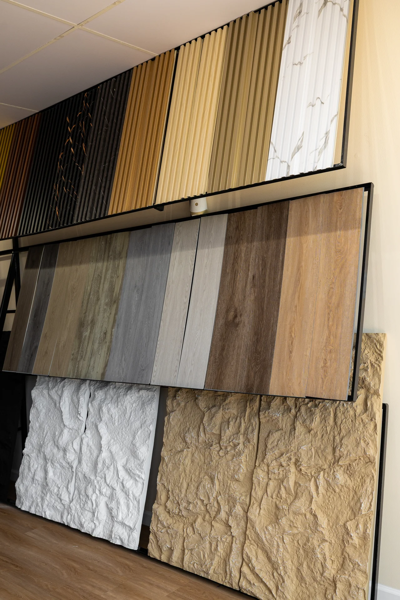 Various samples of decorative wall panels in wood, marble, and textured stone finishes, displayed in a showroom. by PVC Globa